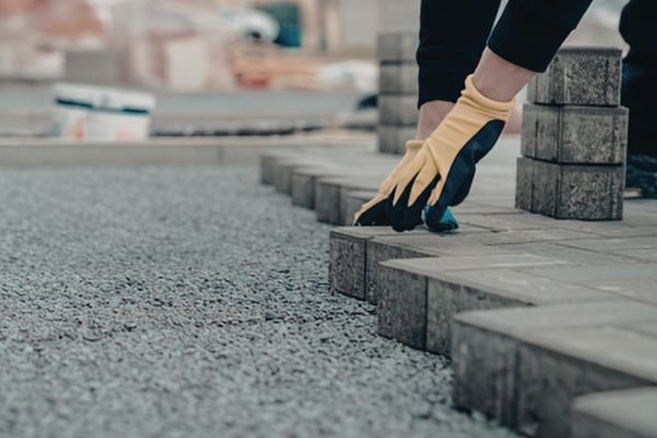 Worker aligning stone pavers on a compacted gravel base to ensure long-term durability and stable installation