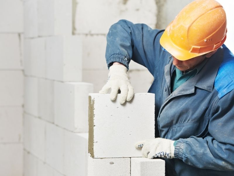 Construction worker installing materials for a stone pavers project during residential construction.