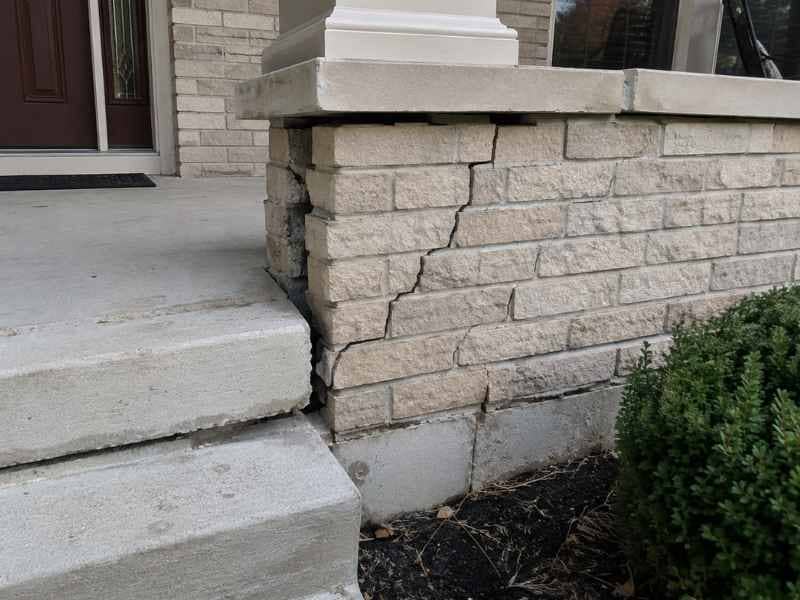Porch brick repair in Huntsville Alabama showing cracked masonry and separation caused by settling concrete.