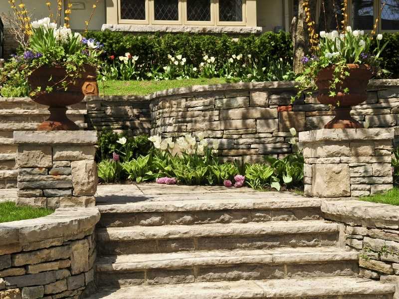 Stone paver steps and multiple landings framed by retaining walls at a front entry in Huntsville, Alabama.